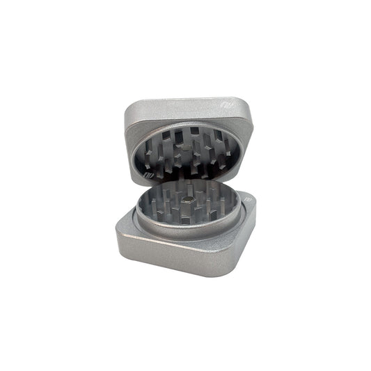 Zweiteiliger Keramik Grinder mit einem Durchmesser von achtundsechzig Millimeter von der Marke NV in der Farbe grau. Quadratische Form, das Teil zum Grinden ist rund. Das Produkt ist vor einem weißen Hintergrund.