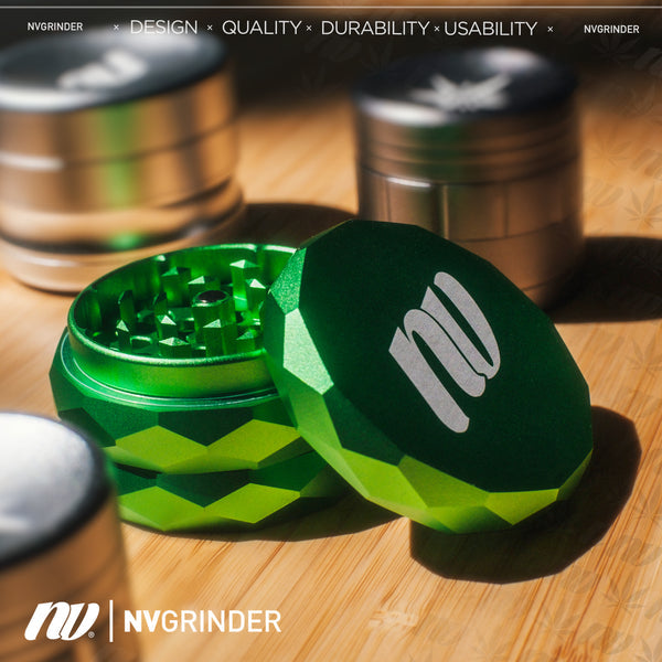Vierteiliger Grinder mit Pyramid Gewinde und einem Durchmesser von dreiundsechzig Millimeter von der Marke NV. Das Logo ist in weiß und mittig auf dem Grinder, der Grinder hat die Farbe grün und das Produkt ist auf einem holzernen Untergrund, dahinter befindet sich unscharf noch zwei weitere Grinder in der Farbe silber.