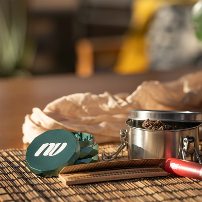 NV Grinder Pyramid Magnet in der Farbe Jungle Green auf einer Bambusunterlage. Daneben stehen Papes und der Hintergrund ist weichgezeichnet.